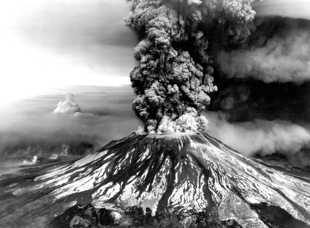 A photograph of Mt Saint Helens erupting in a column of dark smoke and ash. 