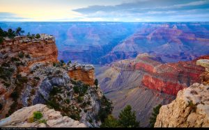 A photograph of the Grand Canyon, with land striped with bright red in the right middle ground and background.